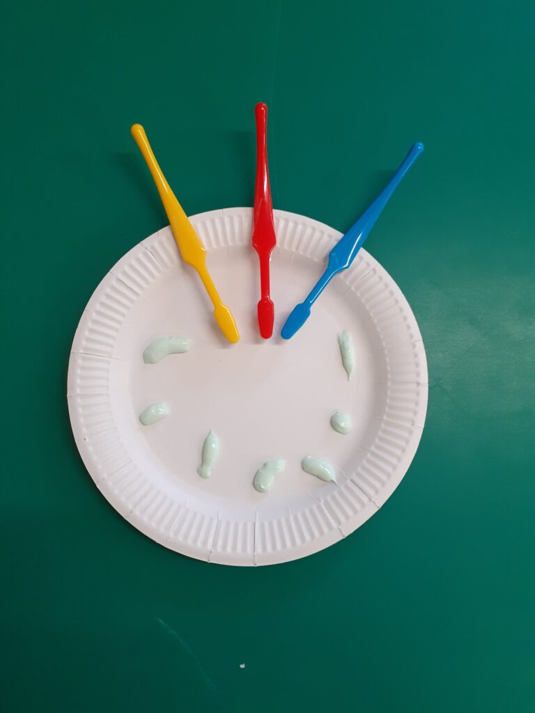 Three toothbrushes and some toothpaste on a paper plate