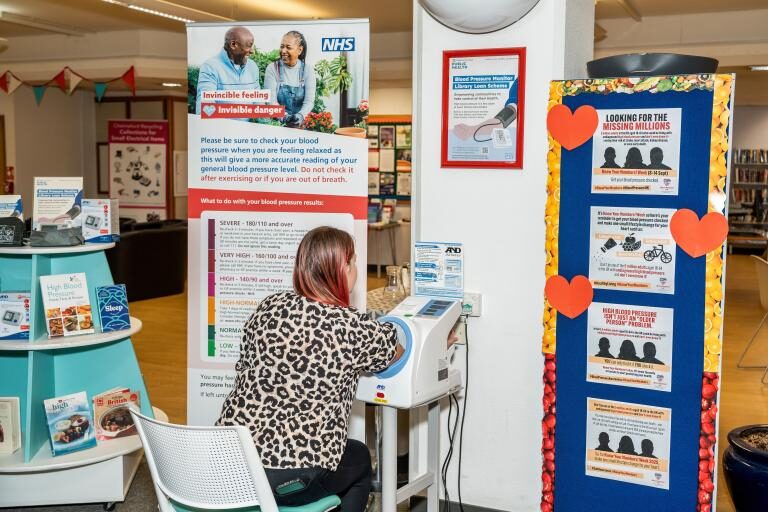Resident using a blood pressure monitor at an Essex library as part of the free blood pressure checks in Essex libraries scheme
