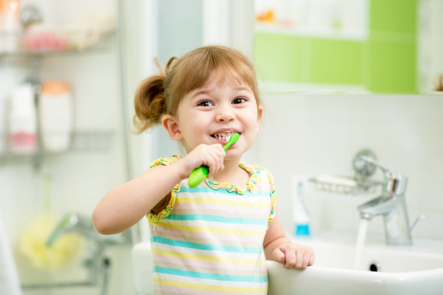 Young girl smiling as she brushes her teeth